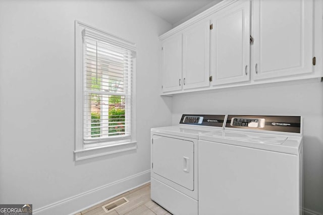 washroom featuring visible vents, cabinet space, baseboards, and washer and clothes dryer