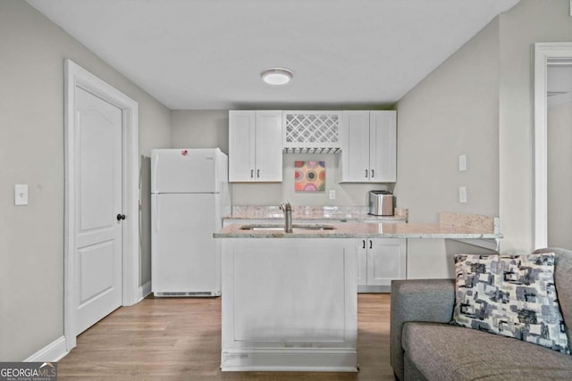 kitchen featuring white cabinetry, light wood-type flooring, a sink, and freestanding refrigerator
