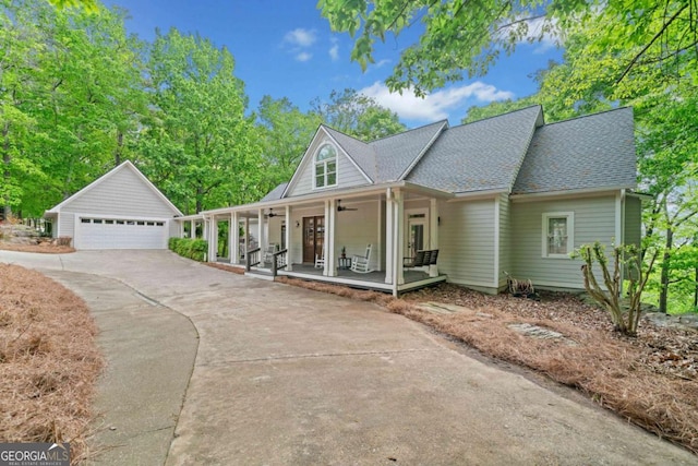 view of front of home featuring covered porch, a shingled roof, an outbuilding, a detached garage, and a ceiling fan