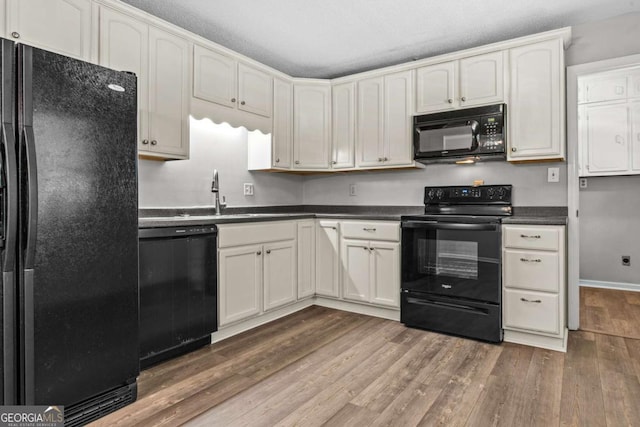 108 Ashwood Pt Unit 196, Eatonton, GA 31024 - kitchen with black appliances, wood finished floors, dark countertops, and white cabinets