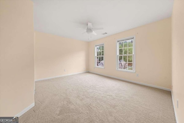 unfurnished room with a ceiling fan, visible vents, carpet, and baseboards
