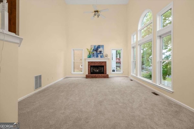 unfurnished living room featuring carpet floors, a towering ceiling, visible vents, and baseboards