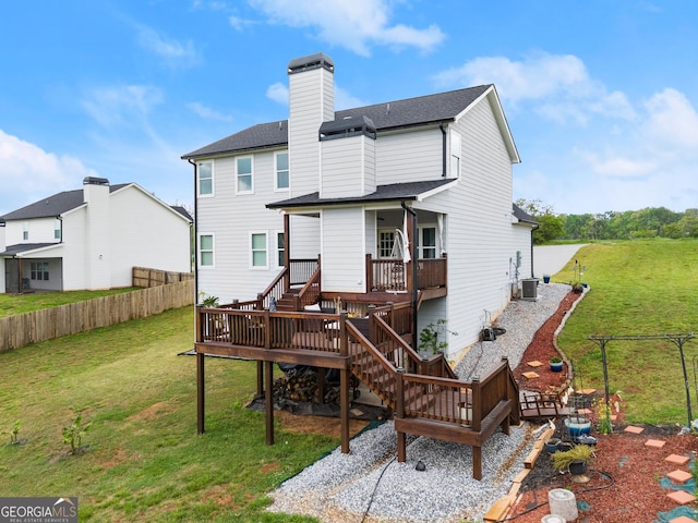 back of house featuring a chimney, fence, stairs, a wooden deck, and a lawn
