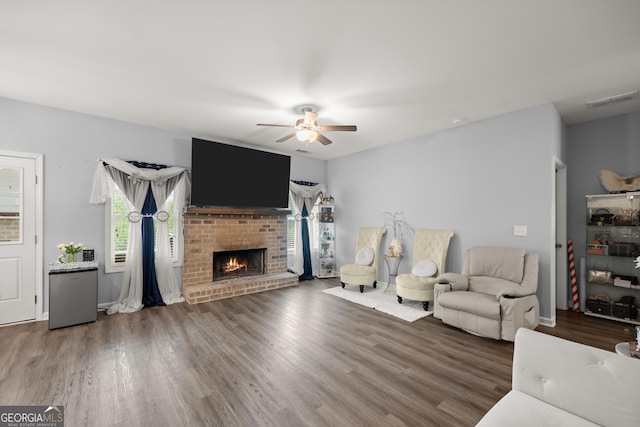 living room with visible vents, wood finished floors, a ceiling fan, and a fireplace