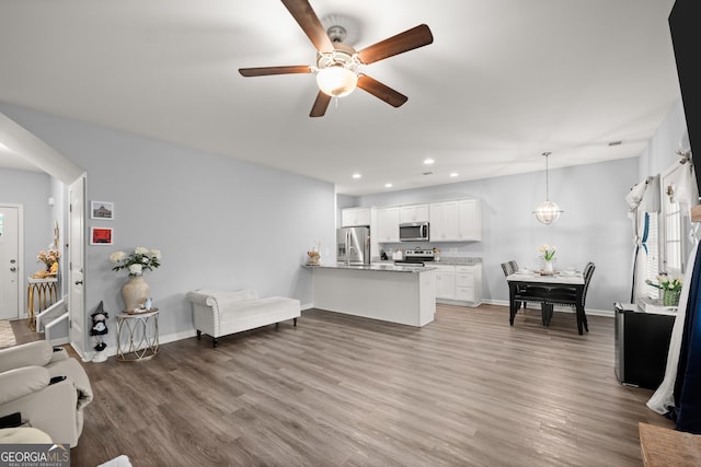 living room featuring wood finished floors, a ceiling fan, recessed lighting, and baseboards