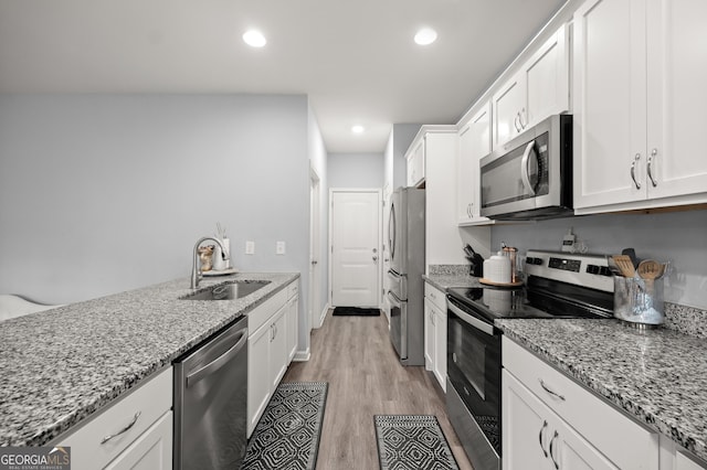 kitchen with recessed lighting, stainless steel appliances, light wood-style floors, white cabinets, and a sink