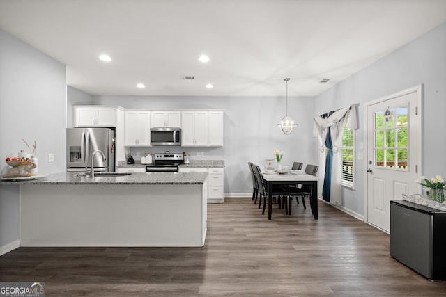 kitchen with light stone counters, white cabinets, a sink, stainless steel appliances, and recessed lighting