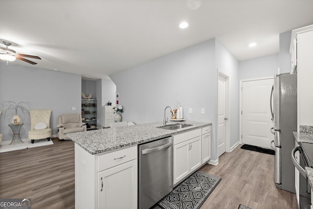 kitchen featuring stainless steel appliances, white cabinets, ceiling fan, a sink, and a peninsula