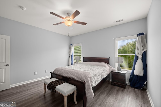 bedroom with baseboards, wood finished floors, and multiple windows