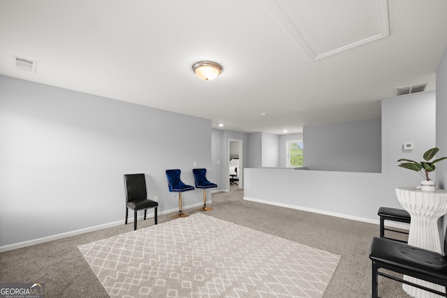 living area featuring baseboards, visible vents, and carpet