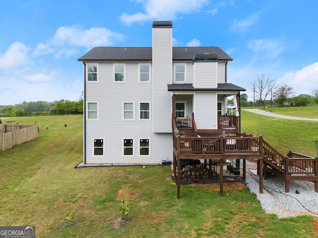 rear view of house with a wooden deck, a yard, and a chimney