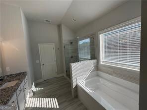 3421 Andover Way, Buford, GA 30519 - full bathroom with a garden tub, vanity, wood finished floors, lofted ceiling, and a shower stall
