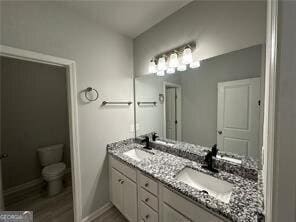 3421 Andover Way, Buford, GA 30519 - bathroom with double vanity, wood finished floors, a sink, baseboards, and toilet