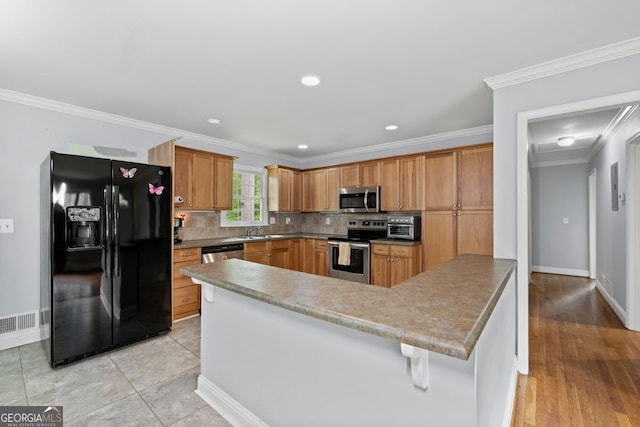 kitchen featuring decorative backsplash, a sink, baseboards, a peninsula, and stainless steel appliances