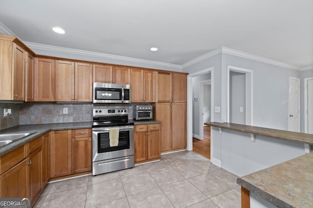 kitchen featuring dark countertops, brown cabinetry, stainless steel appliances, decorative backsplash, and ornamental molding