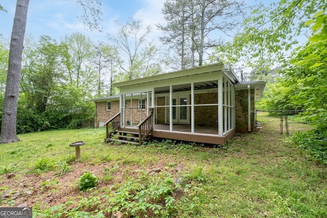rear view of property featuring fence, french doors, a sunroom, brick siding, and a lawn
