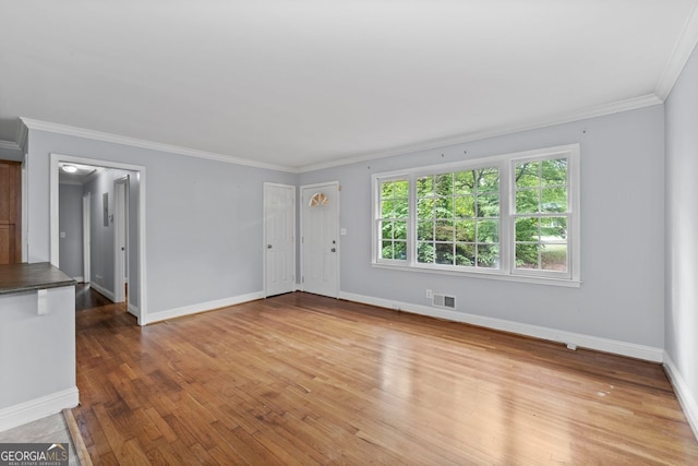 unfurnished living room with baseboards, ornamental molding, hardwood / wood-style floors, and visible vents