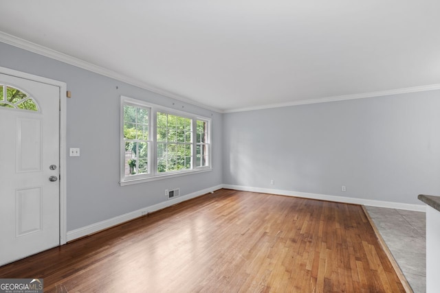 foyer entrance featuring crown molding, baseboards, visible vents, and wood finished floors