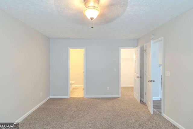 8051 Trinity Park Dr, Riverdale, GA 30296 - unfurnished bedroom with baseboards, light carpet, a spacious closet, and a textured ceiling