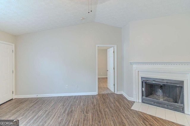 8051 Trinity Park Dr, Riverdale, GA 30296 - unfurnished living room featuring wood finished floors, a textured ceiling, vaulted ceiling, baseboards, and a fireplace with flush hearth