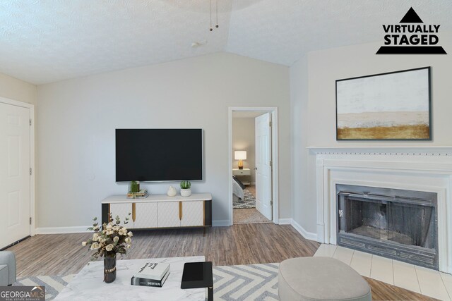 8051 Trinity Park Dr, Riverdale, GA 30296 - living area featuring baseboards, vaulted ceiling, a fireplace, and wood finished floors