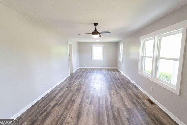unfurnished room with baseboards, visible vents, a ceiling fan, and dark wood-type flooring