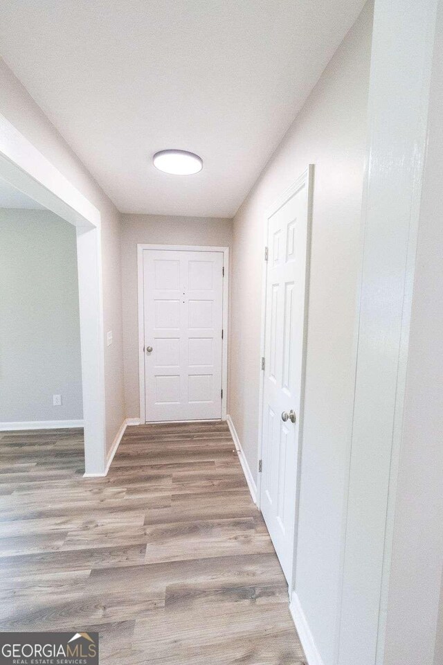 corridor with wood finished floors and baseboards