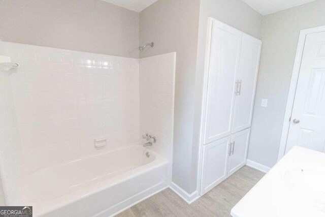 full bath with baseboards, wood finished floors, and shower / tub combination