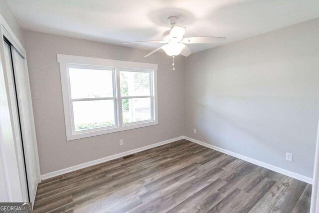 unfurnished bedroom featuring baseboards, visible vents, wood finished floors, and a closet
