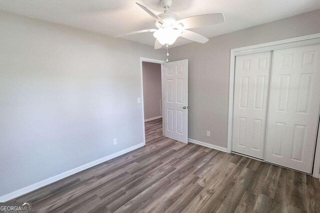 unfurnished bedroom featuring wood finished floors, ceiling fan, a closet, and baseboards