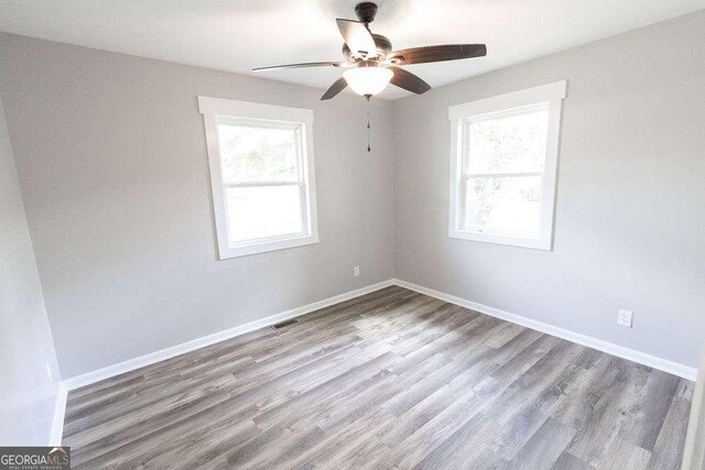 spare room featuring baseboards, visible vents, wood finished floors, and ceiling fan