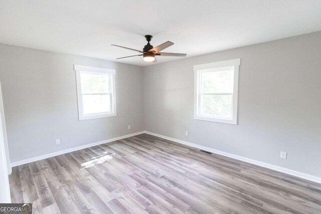 spare room featuring visible vents, ceiling fan, wood finished floors, and baseboards