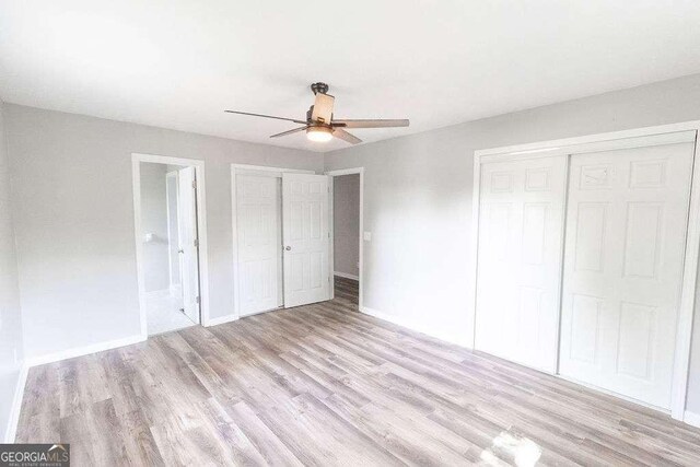 unfurnished bedroom featuring light wood finished floors, a ceiling fan, ensuite bath, and baseboards