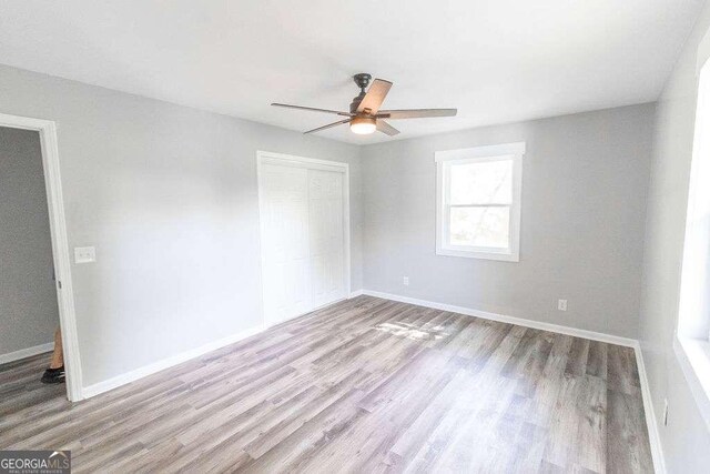 spare room with baseboards, wood finished floors, and a ceiling fan