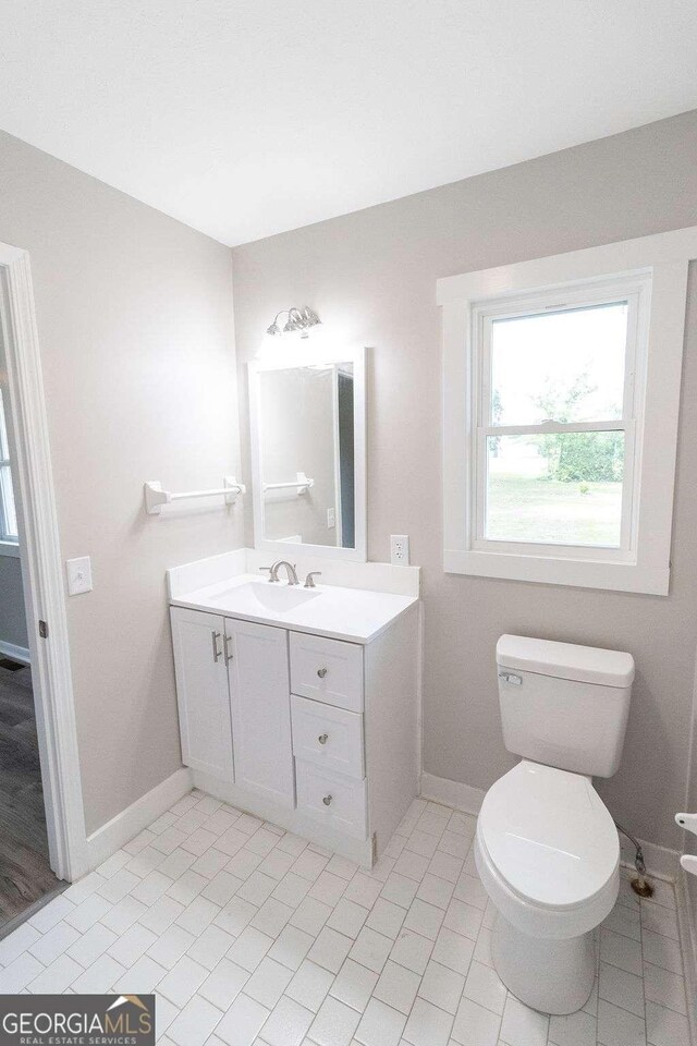 bathroom with toilet, tile patterned flooring, vanity, and baseboards