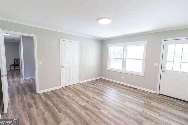 entryway featuring baseboards, ornamental molding, and wood finished floors