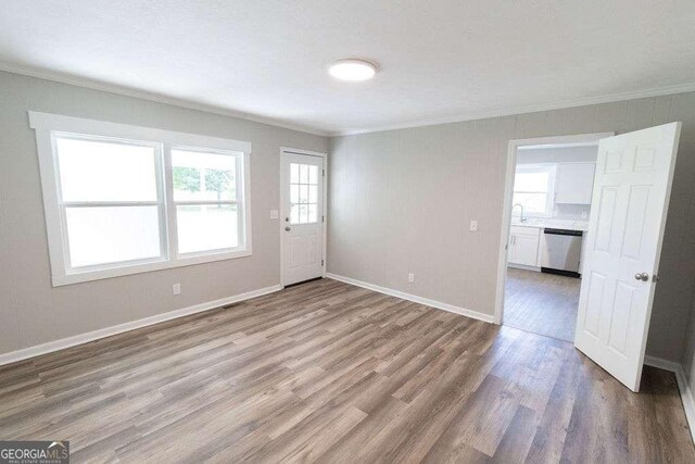 interior space with a sink, wood finished floors, ornamental molding, and baseboards