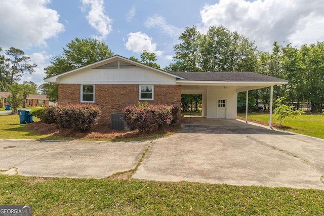 view of front of property with a carport, concrete driveway, a front yard, central AC, and brick siding