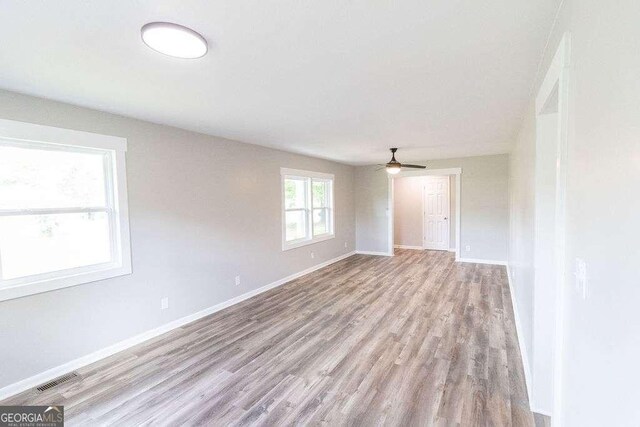 unfurnished living room with visible vents, ceiling fan, wood finished floors, and baseboards