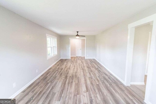 spare room featuring wood finished floors, ceiling fan, and baseboards