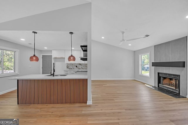 kitchen featuring light countertops, a healthy amount of sunlight, a sink, and a fireplace