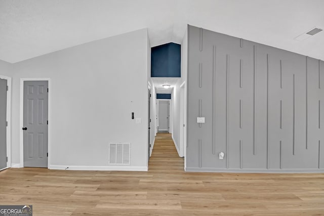 interior space with baseboards, visible vents, light wood-style flooring, and lofted ceiling