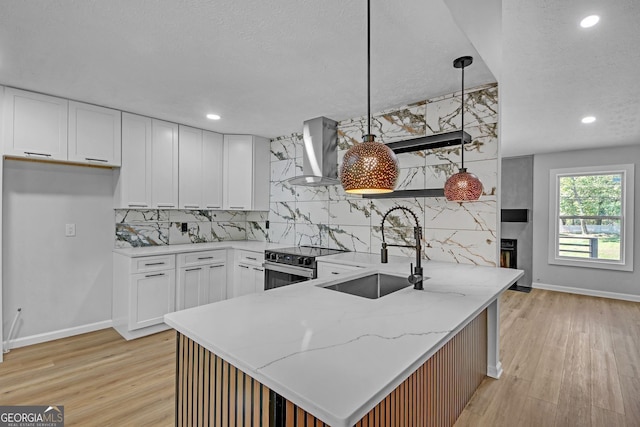 kitchen featuring a sink, light wood-style floors, wall chimney exhaust hood, and stainless steel range with electric stovetop