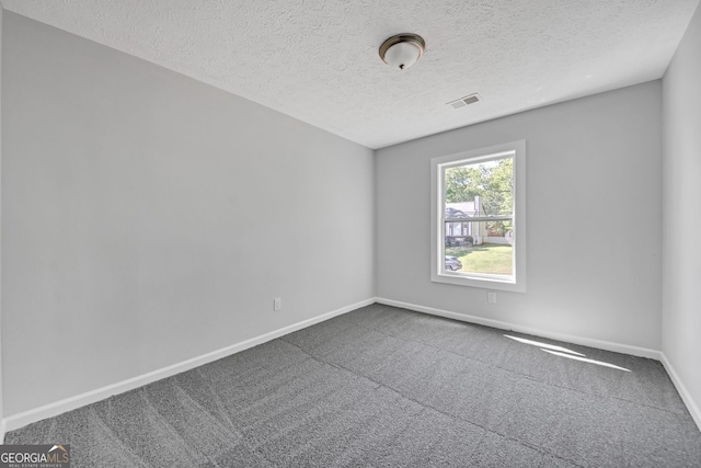 spare room with carpet flooring, a textured ceiling, baseboards, and visible vents