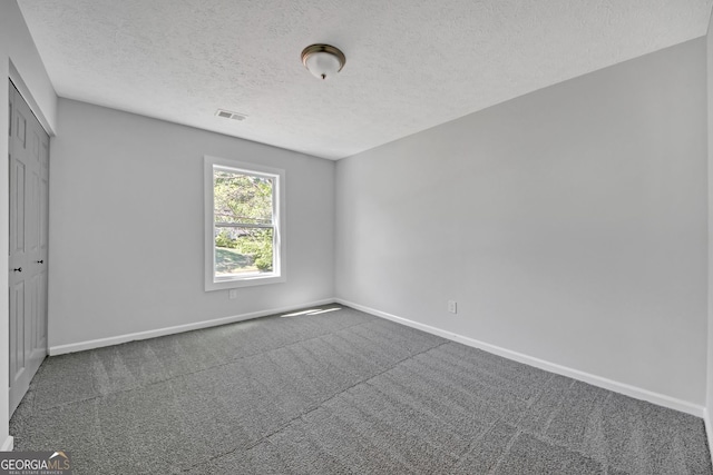 unfurnished bedroom featuring a textured ceiling, visible vents, baseboards, carpet floors, and a closet