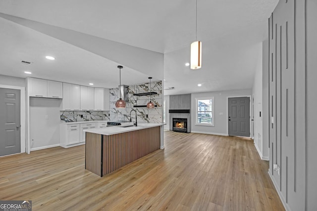 kitchen featuring a sink, light countertops, white cabinets, open floor plan, and light wood-style floors