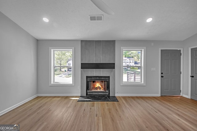 unfurnished living room with baseboards, visible vents, a wealth of natural light, and wood finished floors