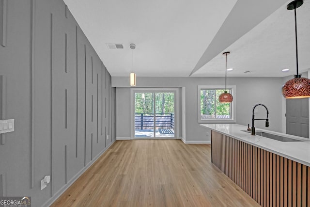 kitchen featuring baseboards, visible vents, a sink, and light wood finished floors