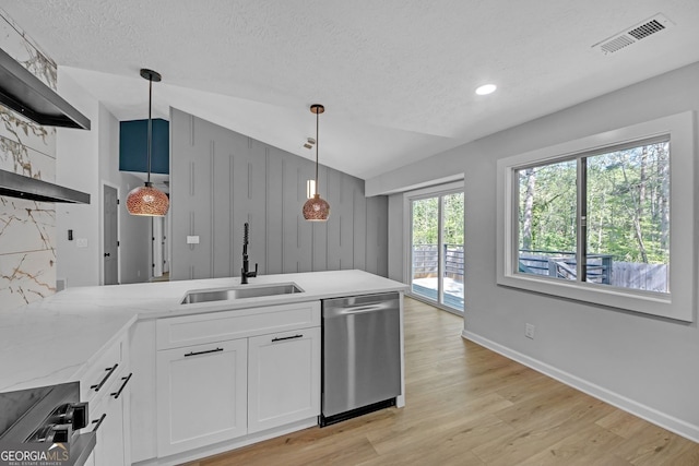 kitchen with visible vents, stainless steel dishwasher, vaulted ceiling, a sink, and a peninsula