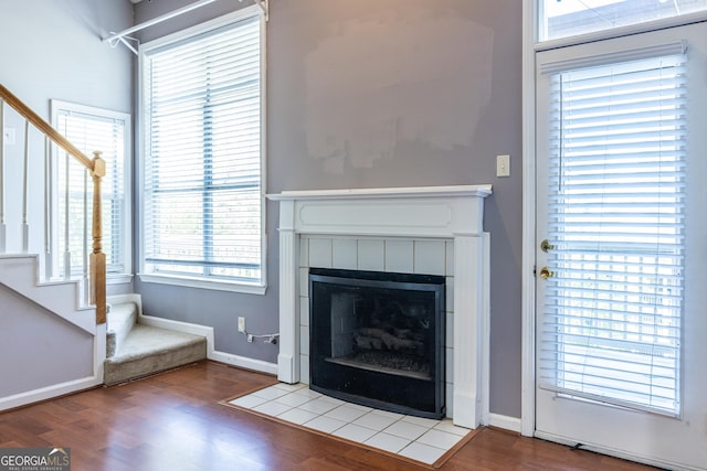 unfurnished living room with stairs, wood finished floors, and a fireplace